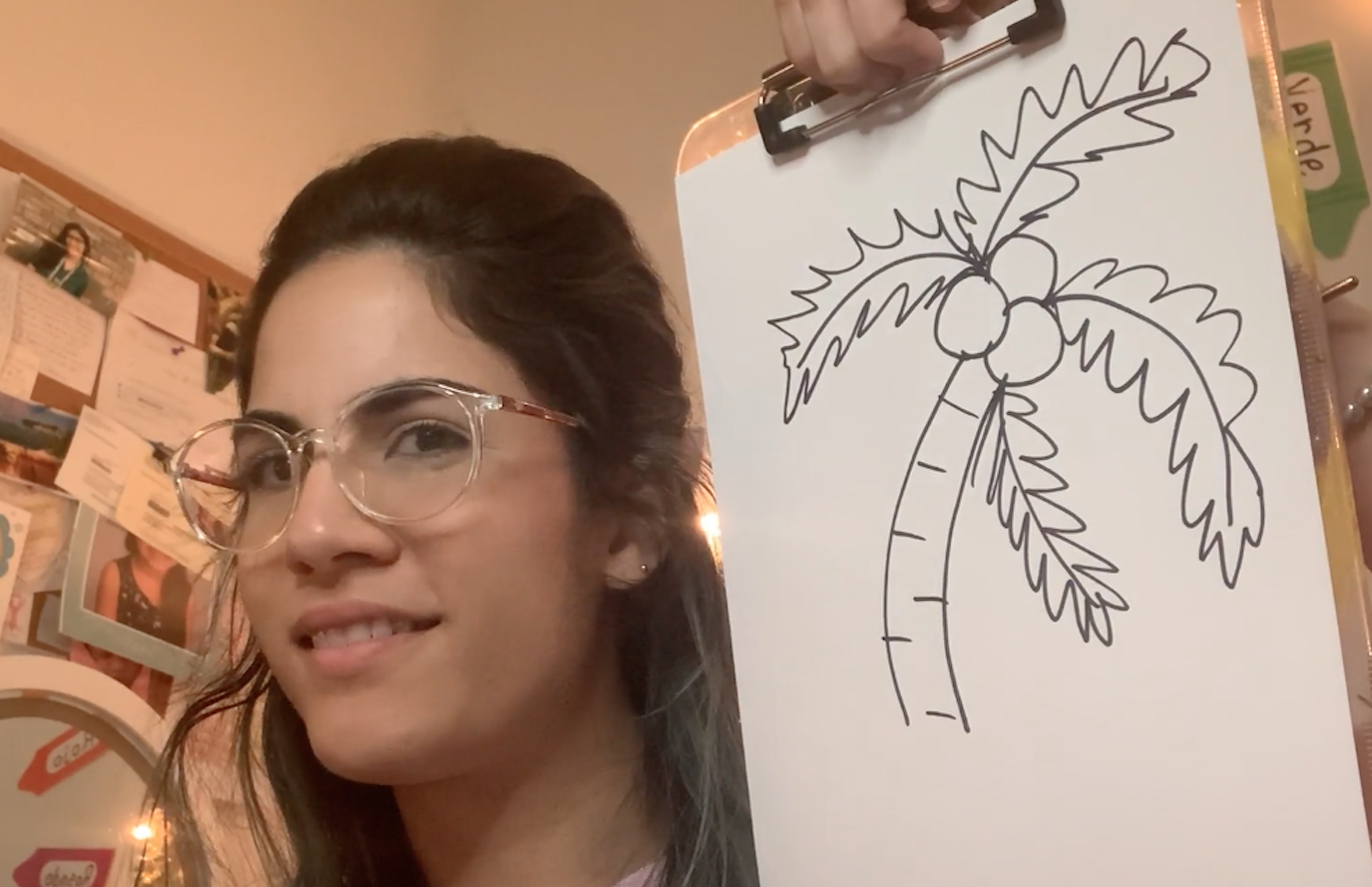 An adult holding up a hand drawn picture of a palm tree.