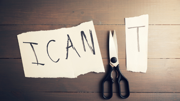 A piece of paper with a scissor visible where cut through the phrase 'I CAN'T' to change to to 'I CAN'