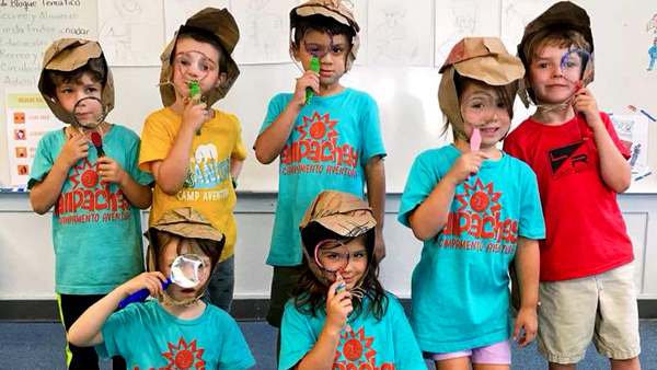 Flight Plan activity image of kids smiling with paper Sherlock Holmes hats and faux magnifying glasses.